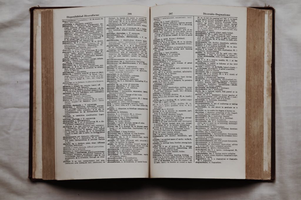 Close-up of an open dictionary showing English and Spanish translations, flat lay view.